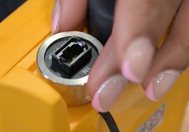 Closeup image of a woman's hand attaching a UniPort™ input adapter to a CertiFiber™ Max tester.